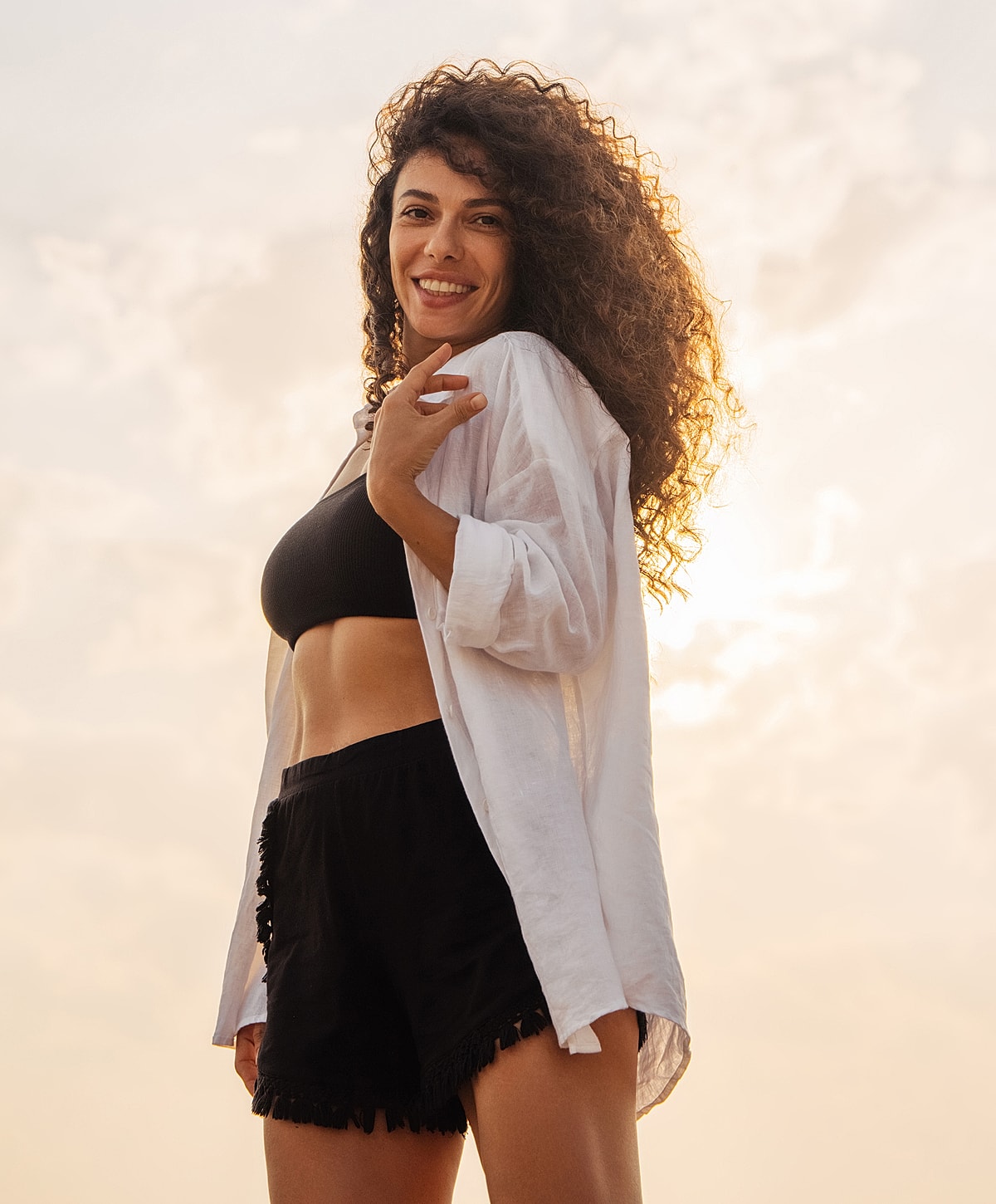 Woman smiling outdoors against a sunset background.