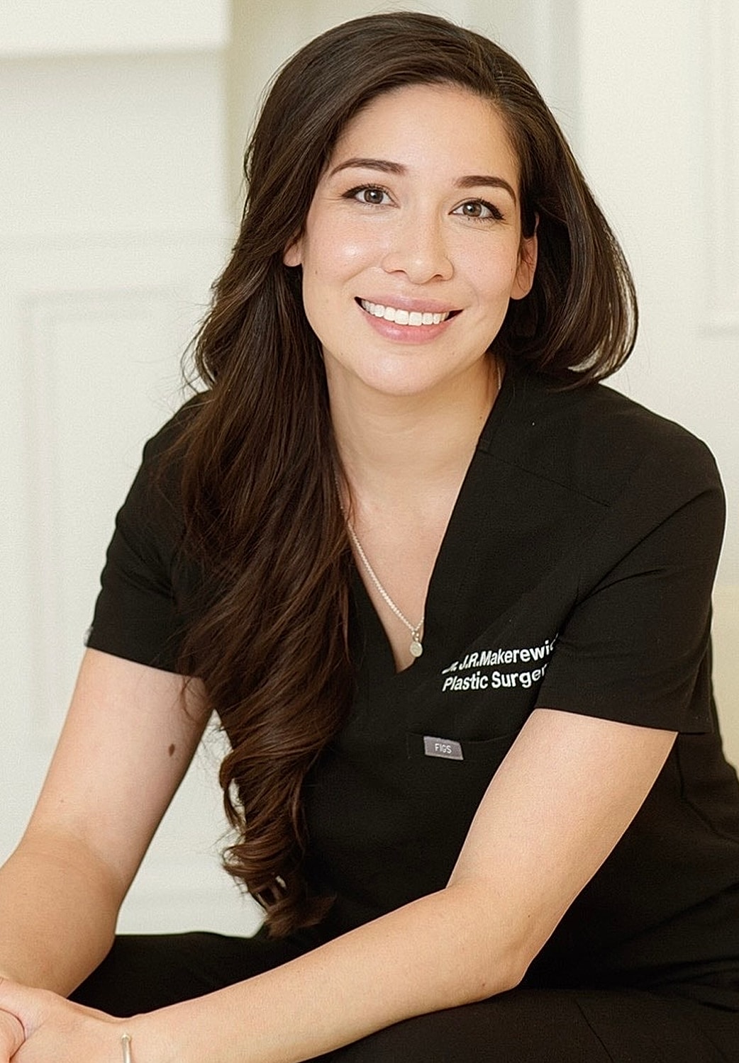 Female plastic surgeon smiling in clinic setting.