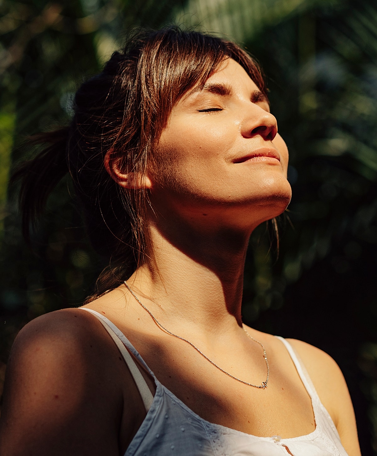 Woman enjoying sunlight with eyes closed outdoors.