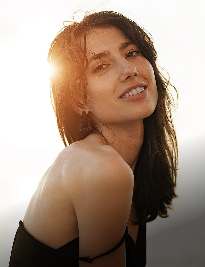 Smiling woman with wavy hair, natural makeup.