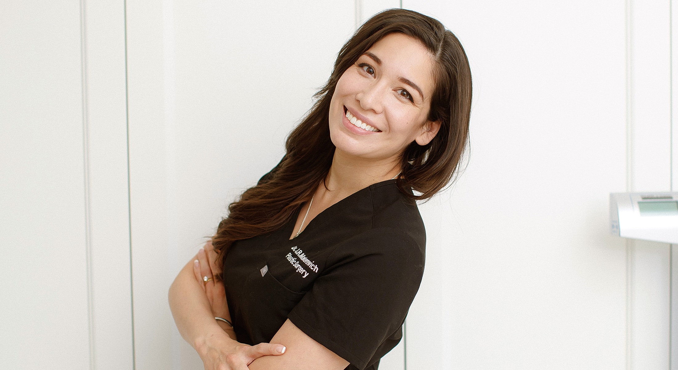 Smiling woman in medical scrubs, arms crossed.