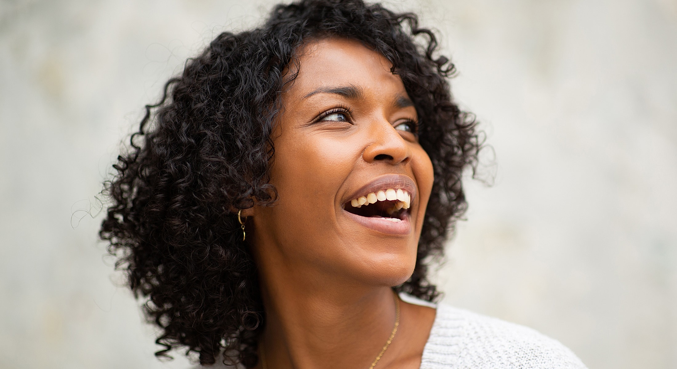 Smiling woman with curly hair against neutral background.
